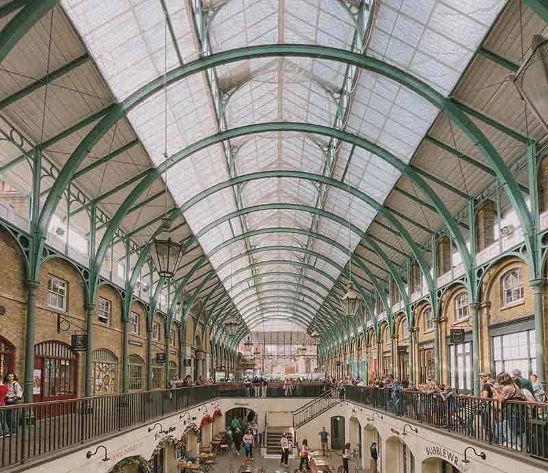Shoppers on the  balustrade below Victorian style cast iron and glass roof. 