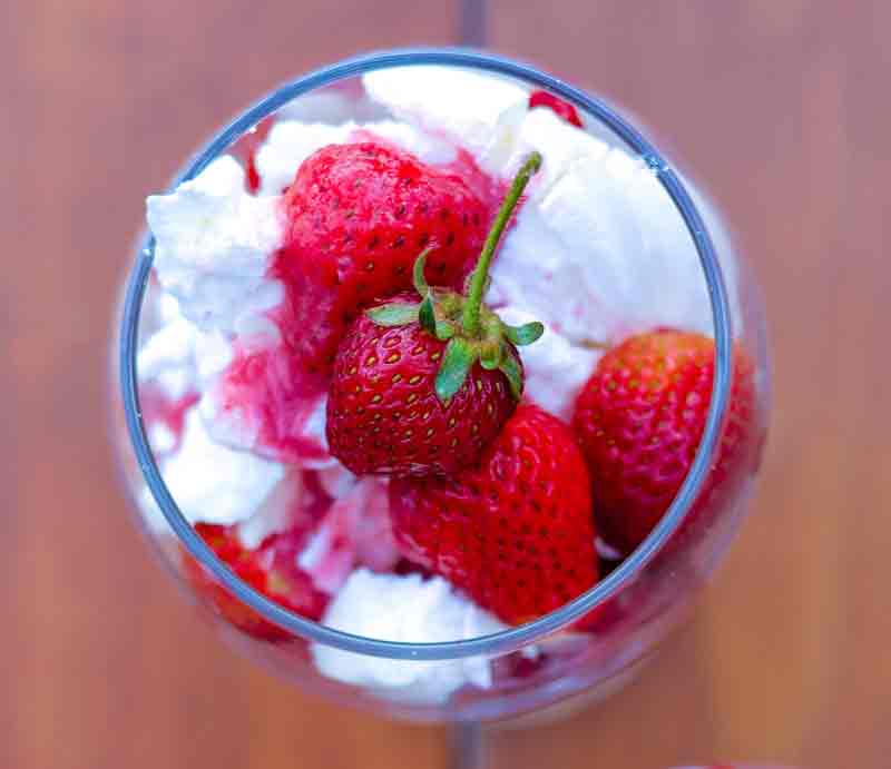 Strawberries, meringue and whipped cream in a dessert bowl.