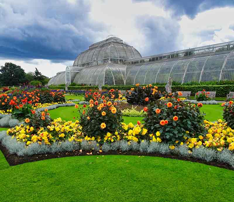 Lawns, brightly coloured planted flower beds and Victorian greenhouse.