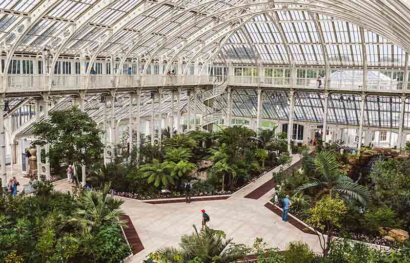Expansive greenhouse built from white-painted wrought iron framework.